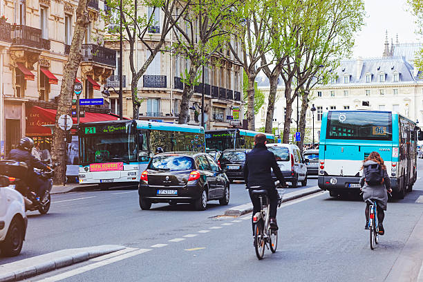 une rue parisienne avec des voitures, des bus et des personnes qui font du vélo